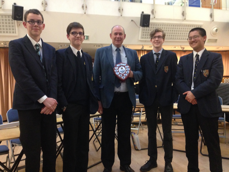a picture of four boys and a teacher with an award