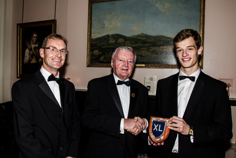 a picture of a student with a award stiid next to two older men