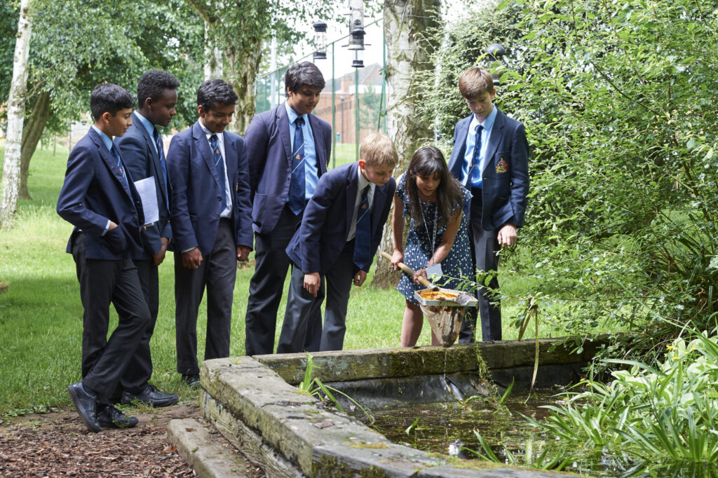 a picture of students and a teacher looking at the pond
