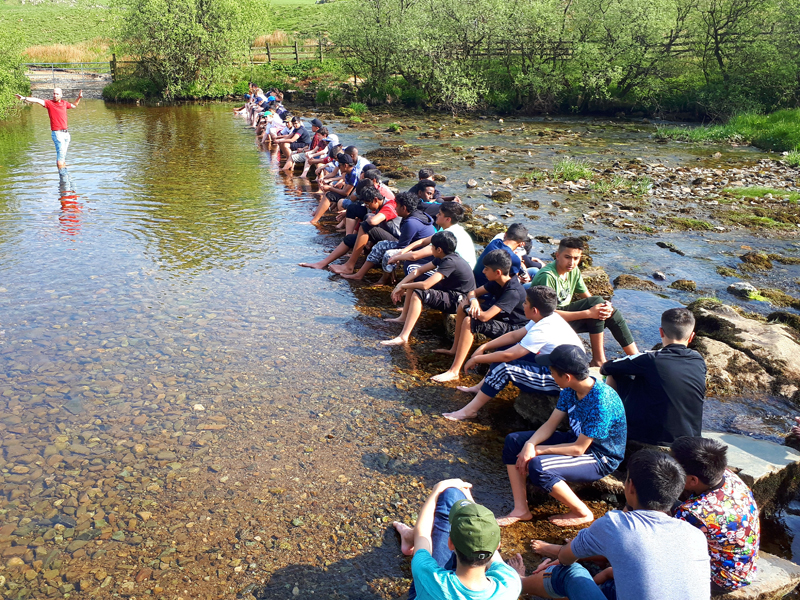 a picture of a goup of students sat in a river