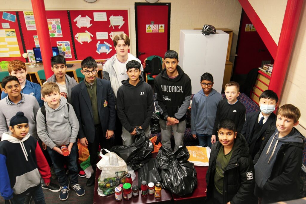 a picture of the Kes schools students, with food for food bank, doing charity work.