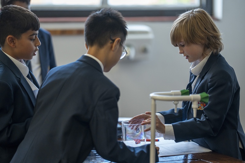 Three Shells pupils (Year 7s) conducting a science experiment involving a glass measuring beaker.