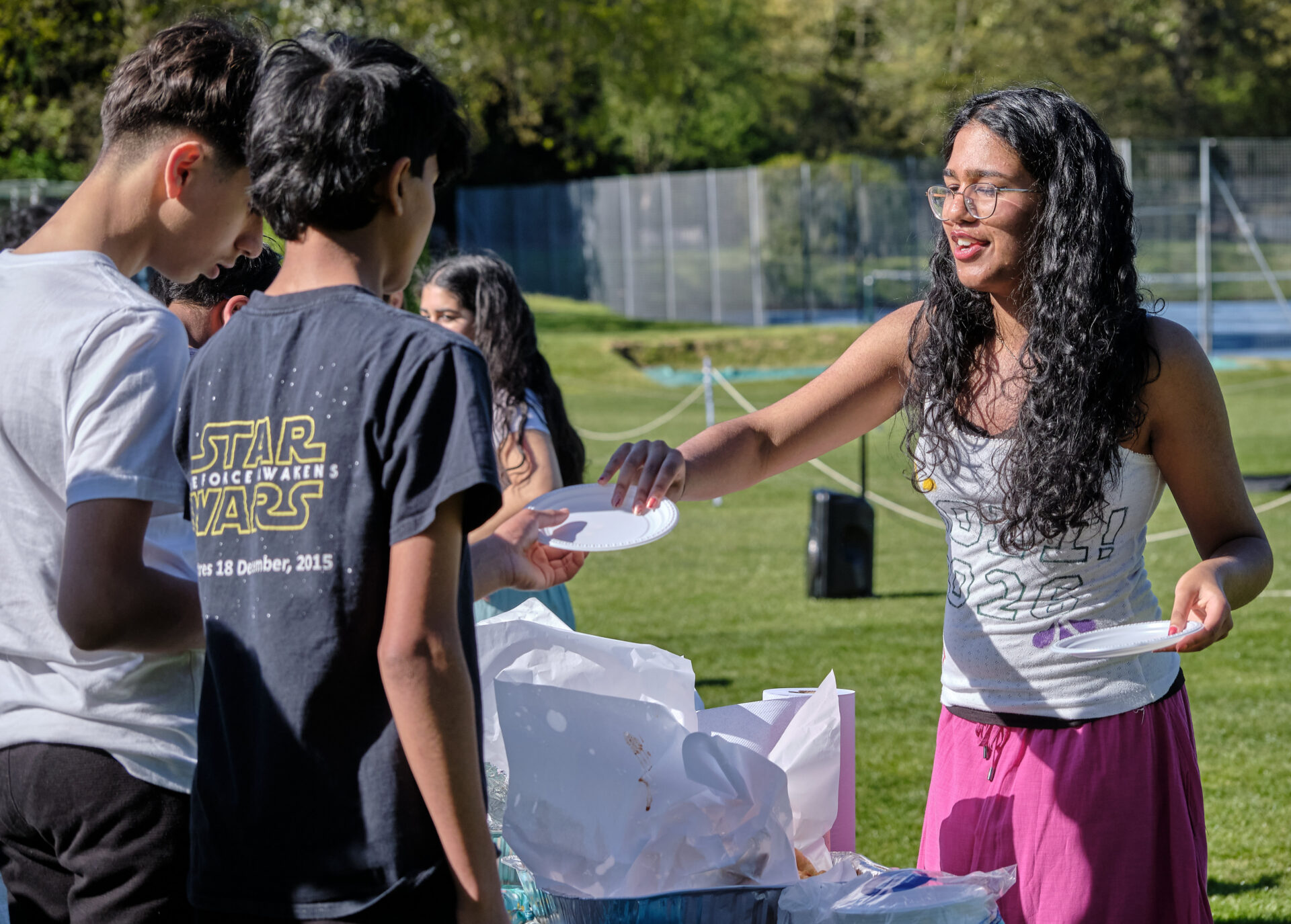 A person serving food on plates at an outdoor gathering.