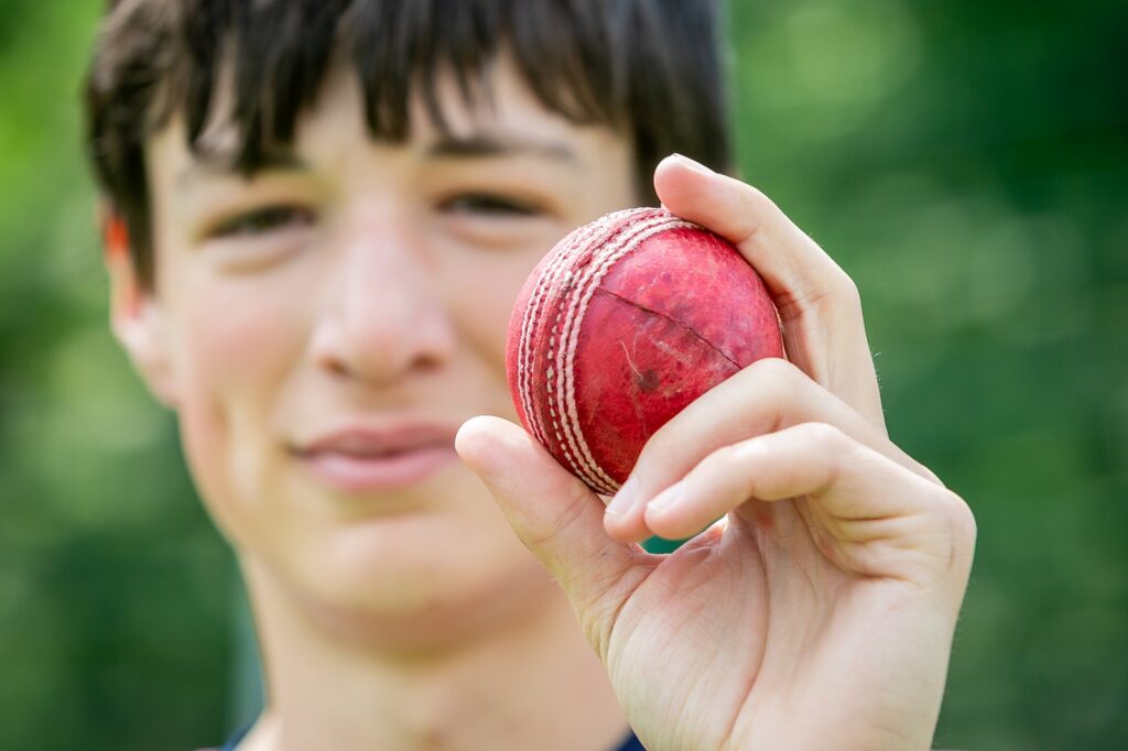 Student cricketer holding up a red cricket ball