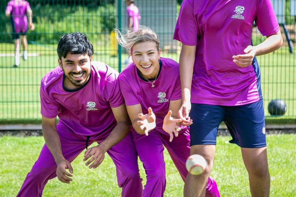 Close up of two male and one female student cricketer waiting to catch a ball