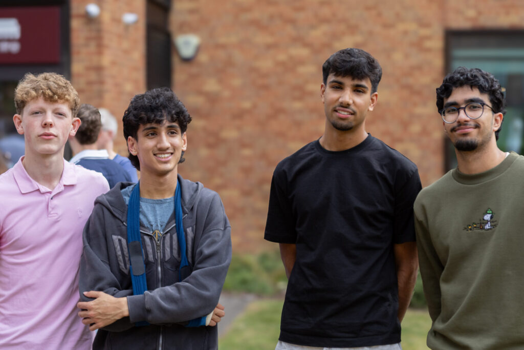 Four young people stand outside a brick building.