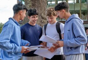 Four students and outdoors talking and sharing exam results.
