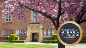 Circular badge reading “FINALIST 2026” and “INDEPENDENT SCHOOLS OF THE YEAR AWARDS,” with “IN ASSOCIATION WITH” and the red “schoolblazer” logo beneath - and the image is of a school building on spring day with a blossom tree in the foreground.